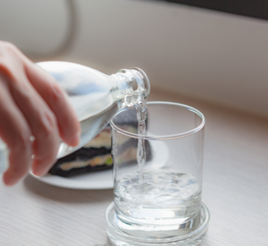 Wasser wird aus Flasche in ein klares Glas gegossen, gesunde Hydratation.